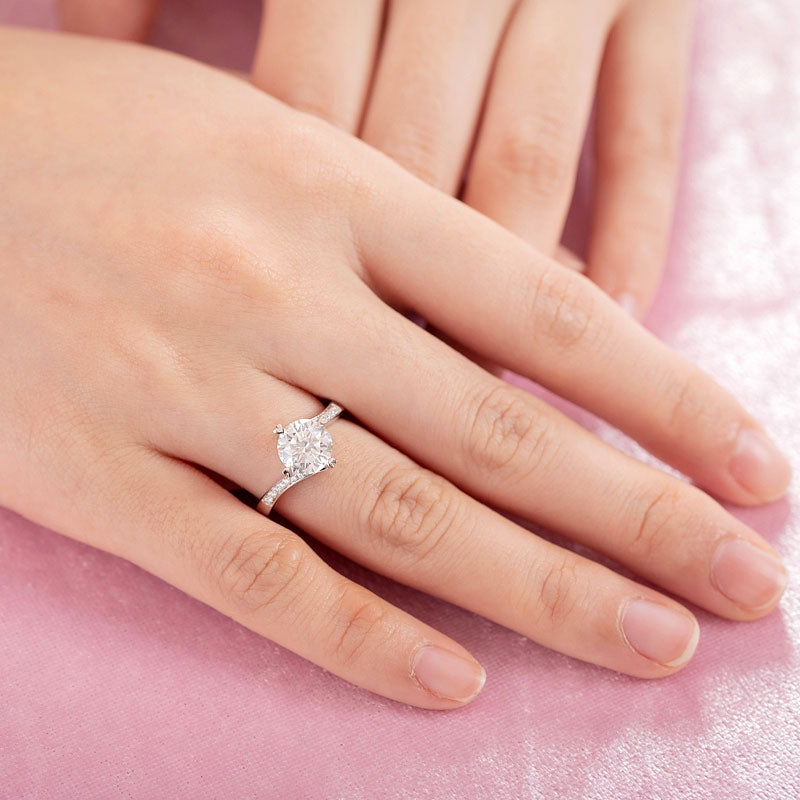 Anillo de compromiso de moissanita redonda de 1,5 quilates con forma de corazón y diamantes en plata de ley.