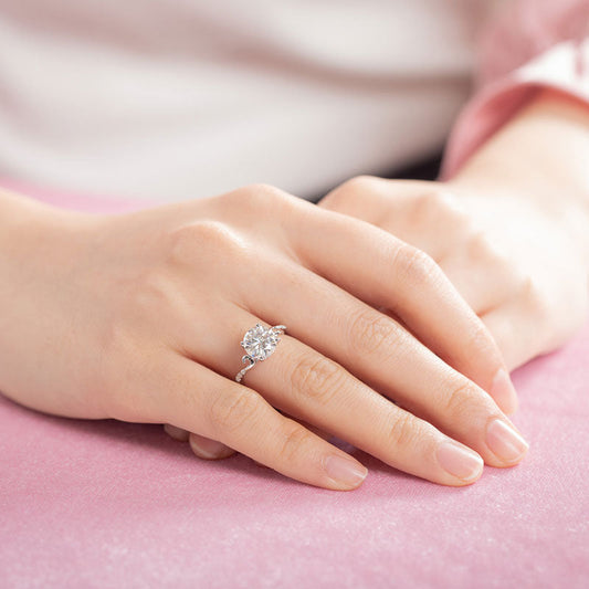 Anillo de compromiso de moissanita redonda de 2 quilates con diamante y cuerpo curvo en plata de ley.