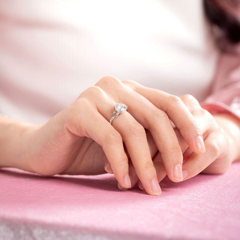 Anillo de compromiso de moissanita redonda de 2 quilates con diamante y cuerpo curvo en plata de ley.