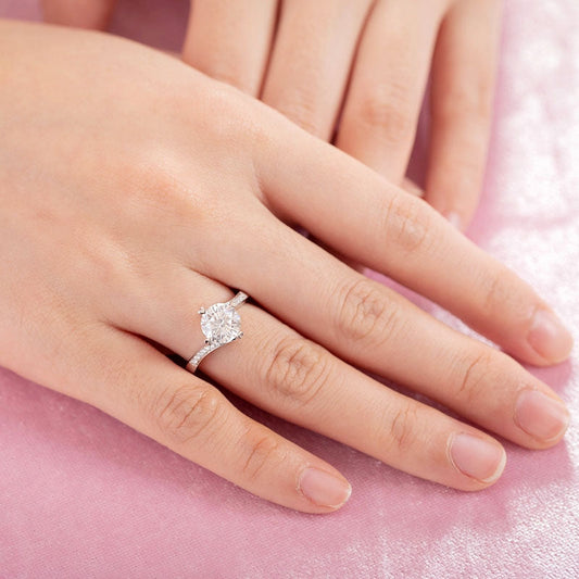 Anillo de compromiso de moissanita redonda de 1,5 quilates con forma de corazón y diamantes en plata de ley.